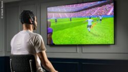 A man wearing an EEG cap sits in front of a screen displaying a video game for neurotraining; copyright: Arkadi Raskin/i-Braintech