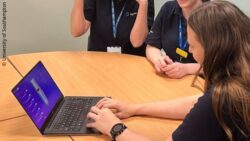 Three people sitting around a desk, one at the front is typing on a latop showing the prosthetic leg; Copyright: University of Southampton