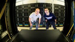 Image: Two men stand in a server room and look into the camera equipped with a fisheye lens; Copyright: Linköping University 