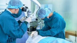Doctor in surgical clothing sitting on a chair with an exoskeleton on his back - exoskeletons in the OR; Copyright: SUITX by Ottobock