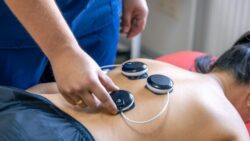 A person's back is being treated with myostimulation therapy